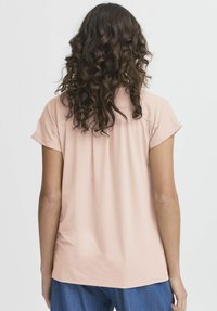 T-shirt rosa chiaro a maniche corte realizzato in un morbido tessuto testurizzato. Collo rotondo e vestibilità rilassata. Il retro presenta un delicato dettaglio di arricciatura.
