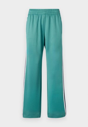 Teal joggebukser med elastisk midje, vide ben og sidelister i marineblått og hvitt. Glatt stoff med matt finish.