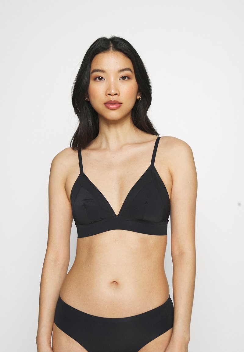 Bralette preto em forma de triângulo com alças finas ajustáveis, tecido macio e detalhes de costura. Combinado com um soutien de bikini preto correspondente.