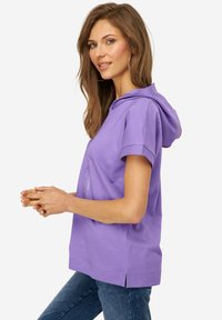 Sudadera corta de manga corta en color morado con un bolsillo frontal, fabricada en tejido suave; presenta una capucha con cordones y aberturas laterales en el dobladillo.