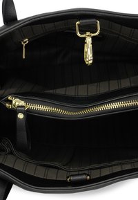 Binnenkant van een zwarte leren handtas, met een gestreepte stofvoering, goudkleurige ritsen en een drukknoopsluiting. Verschillende vakken zichtbaar.