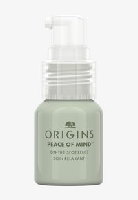 Vihreä lasipullo, jossa on pumppupumppu. Labelissa teksti "Origins Peace of Mind" tummalla tekstillä. Sileä pinta, minimalistinen muotoilu.