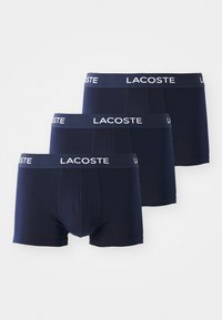 Navy blue cotton boxer briefs with elastic waistband featuring white "Lacoste" logo, smooth texture, and fitted design. Set of three.