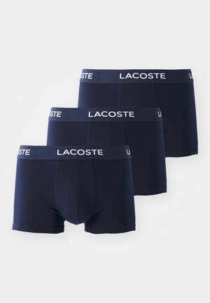 Tumed sinised puuvillased bokserid elastse vöökohtaga, millel on valge "Lacoste" logo, sile tekstuur ja istuv disain. Kolme komplekt.