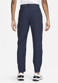 Navy pants in a streamlined design with a smooth texture. Features two back pockets and paired with white and black shoes.