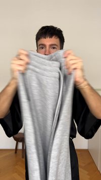 Gray sweatpants held up, featuring an elastic waistband and drawstring. The fabric appears soft with a subtle texture.