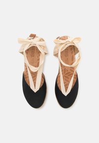 Czarne espadryle z tkaniny, z beżowymi paskami i kokardami, posiadające teksturowaną brązową wkładkę ze wzorem liści.