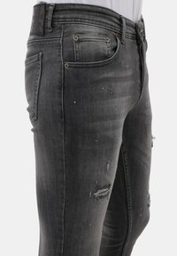 Zwarte denim jeans met een slim fit, voorzien van versleten plekken, subtiele vervaging en een leren patch op de tailleband.