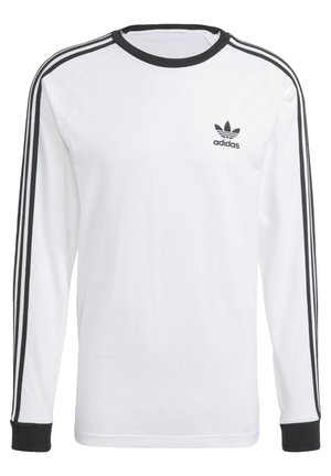 Camiseta de algodón blanca de manga larga con acentos negros, con un cuello redondo y un diseño de tres rayas negras a lo largo de las mangas. Logo de Adidas.