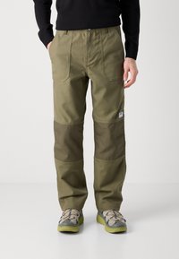 Pantalones de trabajo color verde oliva con parches de rodilla en un verde oscuro contrastante, dos bolsillos frontales y una cinturilla reforzada; confeccionados con una tela resistente.