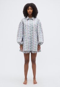 Πολύχρωμο φόρεμα με γεωμετρικά σχέδια, φαρδιές μανίκες, κουμπιά στο μπροστινό μέρος και φαρδύ τελείωμα. Κατασκευασμένο από ελαφρύ ύφασμα.