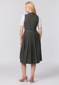 Kleid mit einem enganliegenden dunklen Oberteil, das mit kleinen Blumen bedruckt ist, einem Faltenrock und einem rosa Schürzen-Detail, aus leichtem Stoff gefertigt.