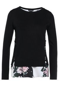 Černý top s dlouhým rukávem, kulatým výstřihem a květinovým vzorem na vrstveném lemu. Má boční otvory s knoflíkovými detaily pro extra ozdobu.