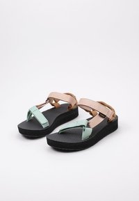 Sandalias ligeras con suela de goma negra, correas en verde menta y marrón, plantilla texturizada y acentos elásticos para un ajuste ajustable.