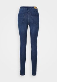 Slim-fit granatowe dżinsy z denimu z pięcioma kieszeniami, z wysokim stanem i delikatną fakturą. Widok z tyłu pokazuje dwie tylne kieszenie.