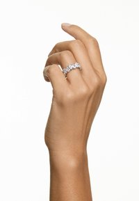 Silberner Ring mit fünf rund geschliffenen, klaren Steinen, gefasst in einer Krappenfassung. Die dargestellte Hand ist entspannt, mit leicht gekrümmten Fingern. Der Hautton ist mittel.