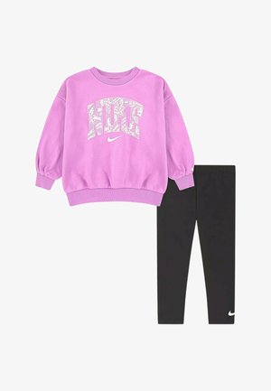 Felpa viola Nike con logo bianco decorato abbinata a leggings neri Nike semplici con un piccolo logo bianco vicino alla caviglia.
