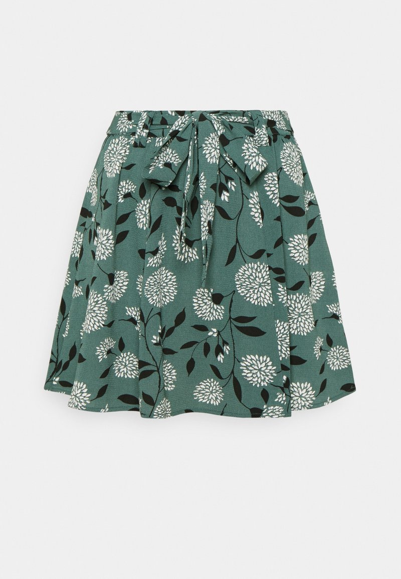 Jupe fleurie verte avec des fleurs blanches et des feuilles noires, avec une ceinture en tissu nouée à la taille et une silhouette évasée.