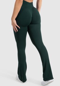 Dopasowane, ciemnozielone legginsy z wysokim stanem, wykonane z elastycznego materiału, z lekkim rozszerzeniem na dole i gładką fakturą.