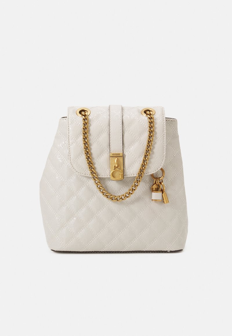 Sac à main matelassé crème avec bandoulière chaîne dorée, détail de serrure dorée et petits charms suspendus dorés et crème sur fond blanc.