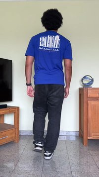 T-shirt azul de manga curta com um design gráfico de vários equipamentos de esqui nas costas. Combinado com jeans pretos e ténis Nike.