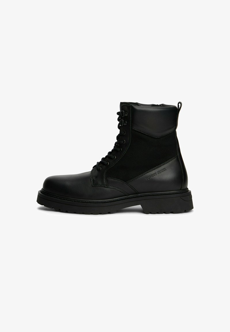 Bottine montante à lacets en cuir noir et tissu avec semelle épaisse et inscription embossée "Tommy Jeans" sur le côté, conçue pour un style robuste.