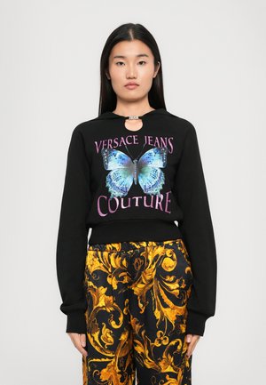 Sudadera negra con un gráfico de mariposa en azul y púrpura, con texto "Versace Jeans Couture" y detalle de escote en forma de llave.