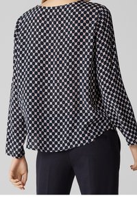 Blusa a maniche lunghe di colore navy con un motivo geometrico di cerchi rosa. Tessuto leggero con una vestibilità rilassata e orlo arrotondato.