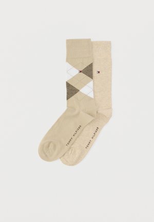 Calzini beige con motivo a rombi argyle in bianco e marrone, e calzino beige tinta unita. Logo del marchio stampato sulle suole.