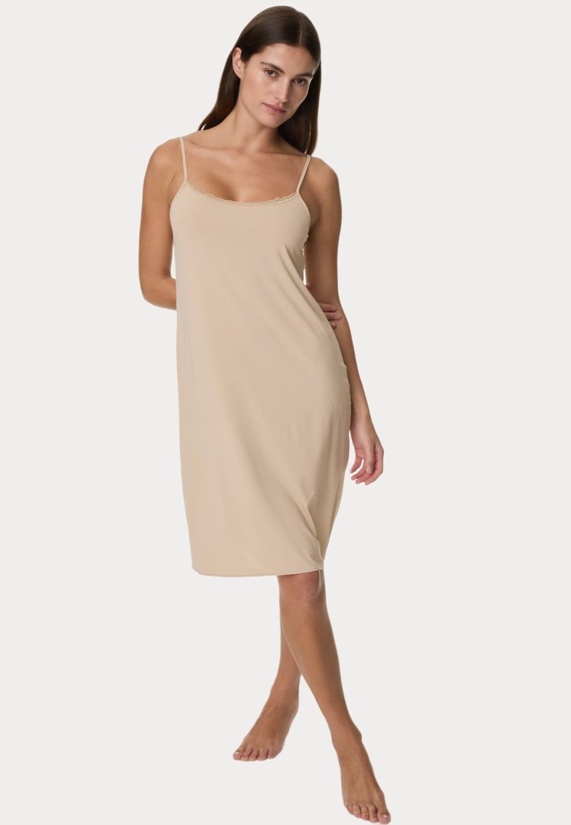 Abito a camicia beige con spalline sottili e bordi in pizzo. Realizzato in tessuto morbido, si ferma poco sopra il ginocchio, mostrando un design semplice e aderente.
