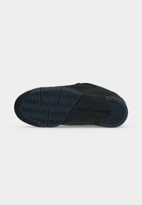 Η σόλα ενός μαύρου sneaker Jordan που δείχνει το σχέδιο ψαροκόκκαλο και τη σήμανση "JORDAN" στην περιοχή της καμάρας.