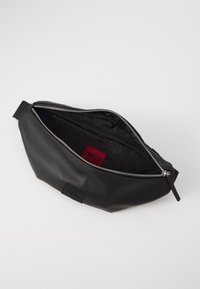 Black leather pouch with a textured finish and silver zipper. Interior features a red logo tag and smooth fabric lining.