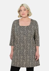 Zwarte en beige tuniek met een geometrisch patroon, voorzien van een vierkante halslijn en driekwartmouwen, gemaakt van zachte, lichtgewicht stof.