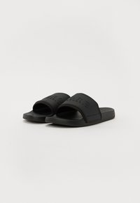 Black rubber slide sandals with a wide strap featuring embossed branding. Textured footbed and flat sole for comfort.