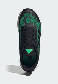 Czarne buty sportowe z zielonymi geometrycznymi wzorami, teksturowanymi nakładkami i czarną siateczką. Posiadają czarne sznurówki oraz zielony akcent na pięcie.