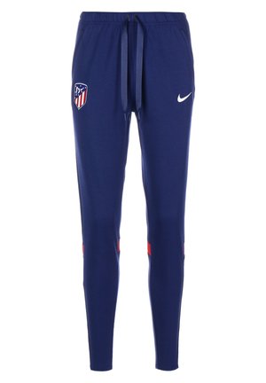 Tmavě modré sportovní kalhoty s nastavitelným pasem, znak klubu Atletico Madrid na levém stehně, bílé logo Nike na pravém stehně a červené akcenty v blízkosti kolen.