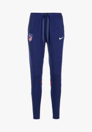 Tmavě modré sportovní kalhoty s nastavitelným pasem, znak klubu Atletico Madrid na levém stehně, bílé logo Nike na pravém stehně a červené akcenty v blízkosti kolen.