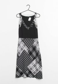 Sleeveless black dress featuring a plaid pattern in shades of gray. Textured accents on the neckline and a flowing silhouette.