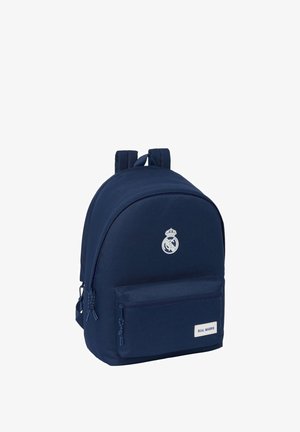 Zaino blu navy con forma arrotondata, tasca con zip frontale, logo argentato e spallacci doppi imbottiti per comfort e supporto.