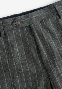 Graue Wollhosen mit vertikalen Streifen, gefalteter Vorderseite und einem braunen Knopfverschluss am Bund. Texturierte Stoffdetails sichtbar.