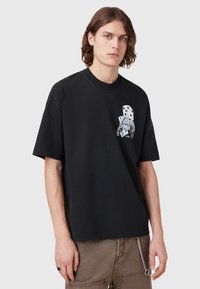 Black short-sleeve t-shirt featuring a graphic design of dice and playing cards on the left chest, made of soft cotton material.