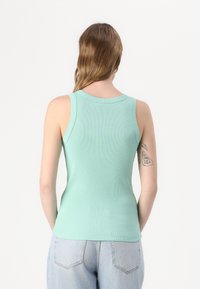 Mintgrønn ribbestrikket tanktopp med rund hals og uten ermer, som viser en tettsittende fasong og ren finish.