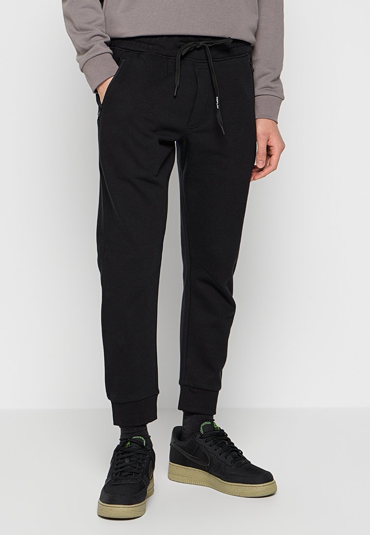 Pantaloni da jogging neri con polsini elasticizzati, vita con cordino e tasche laterali. Realizzati in tessuto morbido, presentano una superficie liscia e un design aderente.