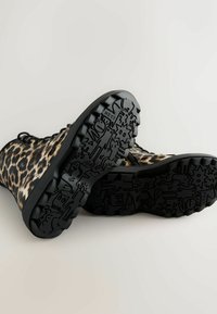 Leopardmønstrede ankelstøvler med en struktureret sort gummisål, der har et grafisk mønster og et solidt snørebånddesign.
