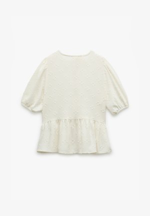 Haut ivoire pâle avec des manches courtes à volants, un ourlet peplum froncé, un motif floral texturé et un col rond.