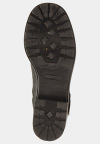 Czarna gumowa podeszwa z głębokimi rowkami i wzorami w kształcie diamentu. Solidna konstrukcja z teksturowanym górnym brzegiem dla lepszego chwytu. Logo "Clarks" na podeszwie.