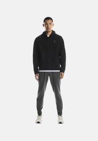 Musta vetoketjullinen huppari, jossa on huppu ja rintamuksessa logo. Yhdistetty harmaisiin sporttihousuihin ja valkoisiin tennareihin. Yksinkertainen ja istuva malli.