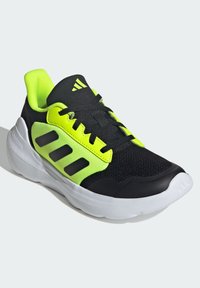 Black and neon green athletic shoe with a mesh upper, three stripe design on the side, and a white rubber sole. Features a padded collar.