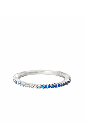 Anillo de plata con piedras preciosas pequeñas azules y claras alternadas alrededor de la banda sobre un fondo blanco.