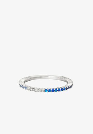 Anillo de plata con piedras preciosas pequeñas azules y claras alternadas alrededor de la banda sobre un fondo blanco.